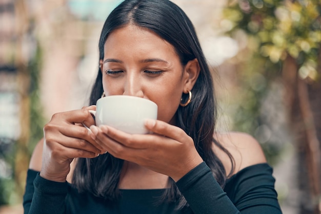 Femme relaxante tenant un café dans la joie à l'extérieur Femme paisible, calme et sans stress sirotant une tasse de thé dans un café à l'extérieur