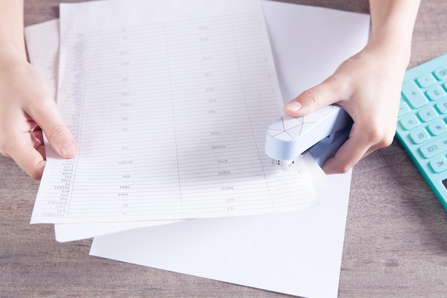 La femme relie des papiers avec une agrafeuse