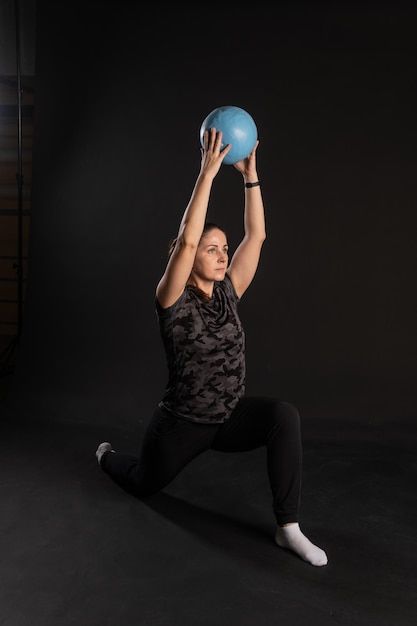 Femme de remise en forme avec Aqua ball se dresse dans un rack Faire du sport sur fond noir