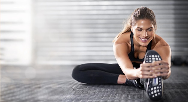 Femme de remise en forme et étirement des jambes sur la maquette en vue de l'exercice d'entraînement ou de l'entraînement sur le sol de la salle de gym
