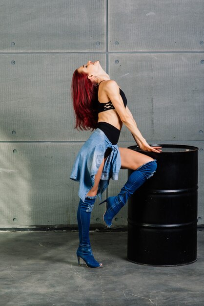 Femme de remise en forme sur fond de béton de ciment près d'un baril noir