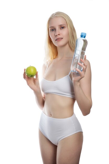 Femme de remise en forme heureux souriant tenant une bouteille de pomme et d'eau. Photo de mode de vie sain du modèle de fitness caucasien isolé sur fond blanc.