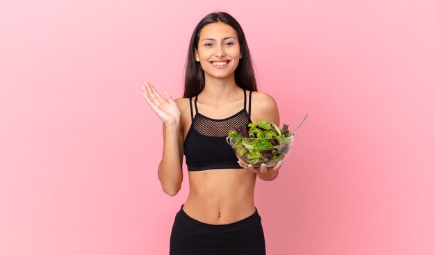 Femme de remise en forme hispanique se sentant heureuse, surprise de réaliser une solution ou une idée et tenant une salade