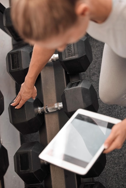 Photo femme de remise en forme et maquette de tablette pour l'exercice de didacticiel d'haltérophilie ou planifier l'entraînement et la planification au gymnase mains de femme active avec écran tactile pour l'entraînement en ligne avec des haltères