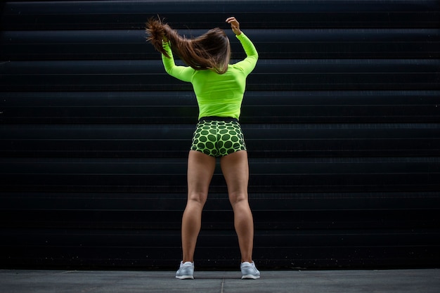 Femme de remise en forme musculaire avec des jambes fortes faisant sa queue de cheval cheveux avant l'entraînement.