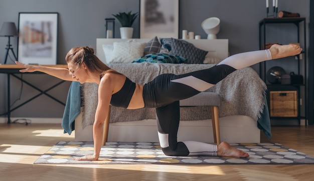 Femme de remise en forme pratiquant le yoga faisant de l'exercice de chien d'oiseau.