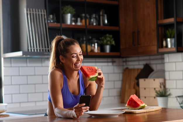 Femme de remise en forme relaxante en train de manger un petit-déjeuner aux fruits de la pastèque après l'exercice de yoga du matin