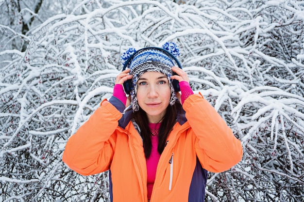 Femme de remise en forme sportive écoutant de la musique avec des écouteurs à l'extérieur dans le parc d'hiver femme active faisant du jogging sur