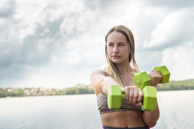 Femme de remise en forme en tenue de sport avec des haltères à l'extérieur