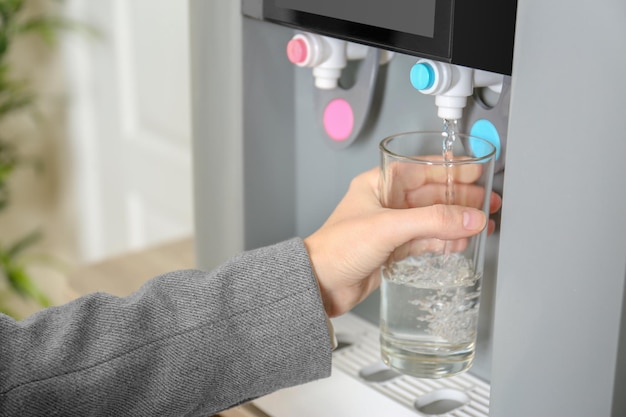 Femme remplissant le verre du refroidisseur d'eau libre