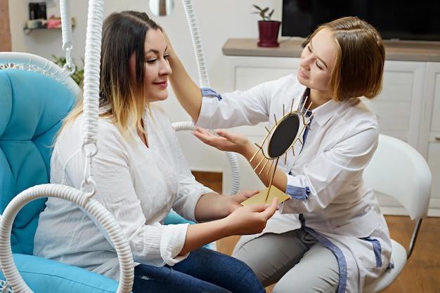 Une femme rend visite à un jeune médecin cosmétologue Le médecin consulte le patient