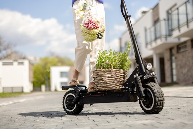 Femme rentrant à la maison avec des légumes frais sur un scooter électrique