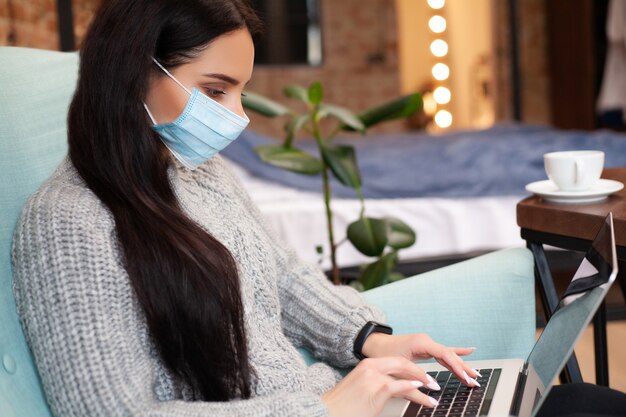 Femme reste à la maison pendant une épidémie et travaille sur un ordinateur portable