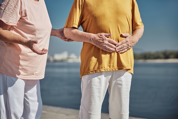 une femme retraitée debout à côté de son conjoint souffrant d'une douleur abdominale