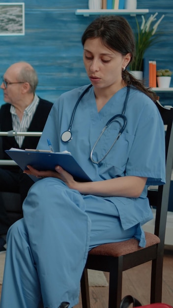 Femme retraitée handicapée parlant à une infirmière pour un examen médical dans une maison de retraite. Assistant de santé consultant un patient âgé assis en fauteuil roulant pour le soutien et l'assistance.