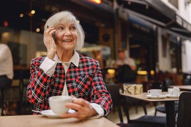 Femme retraitée positive prenant un café au café