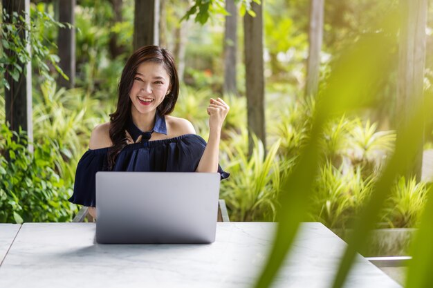 Femme réussie utilisant un ordinateur portable avec les bras levés