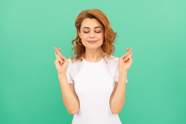 Femme rêveuse aux cheveux bouclés faire un vœu mannequin femme joli look de jeune fille portrait de dame rousse sur fond bleu exprimer des émotions positives