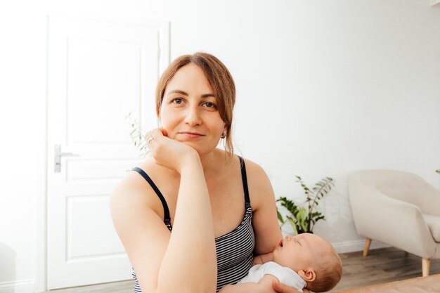 Femme rêveuse avec bébé mignon dormant dans les bras