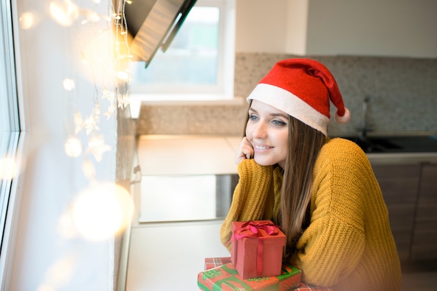 Femme rêveuse avec des cadeaux de vacances