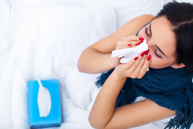 Femme avec un rhume sur le lit sous la couverture