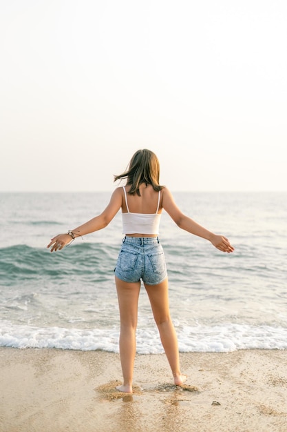Femme sur le rivage de la plage par derrière