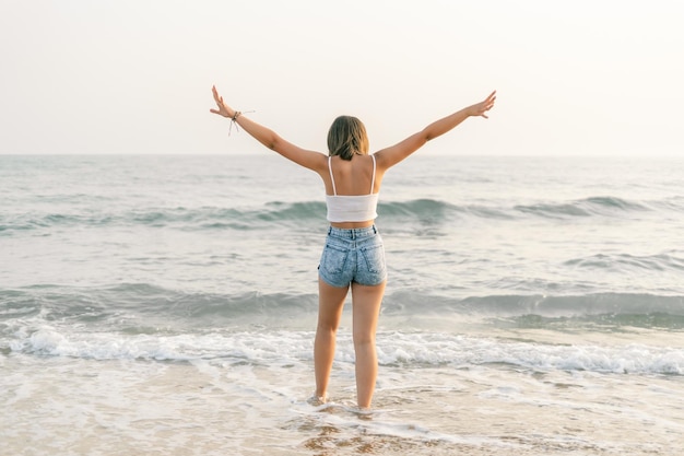 Femme sur le rivage de la plage par derrière