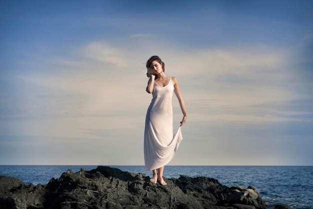 Une femme en robe blanche au bord de la mer