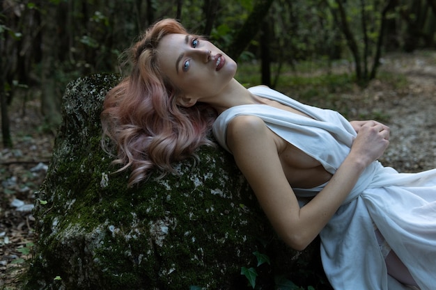 Une femme en robe blanche au milieu de la forêt