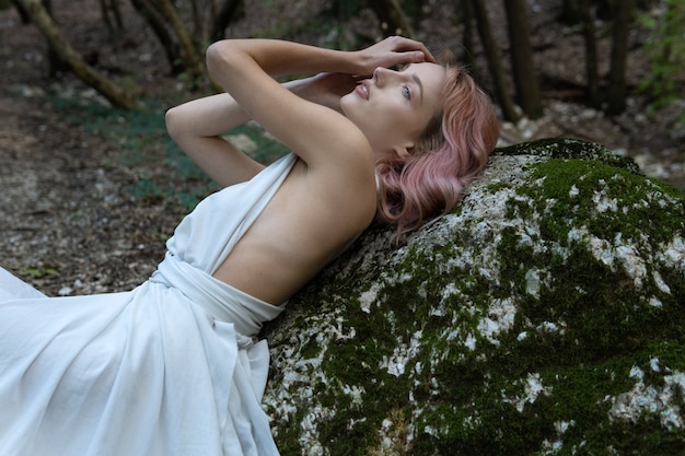 Une femme en robe blanche au milieu de la forêt