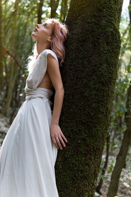 Une femme en robe blanche au milieu de la forêt
