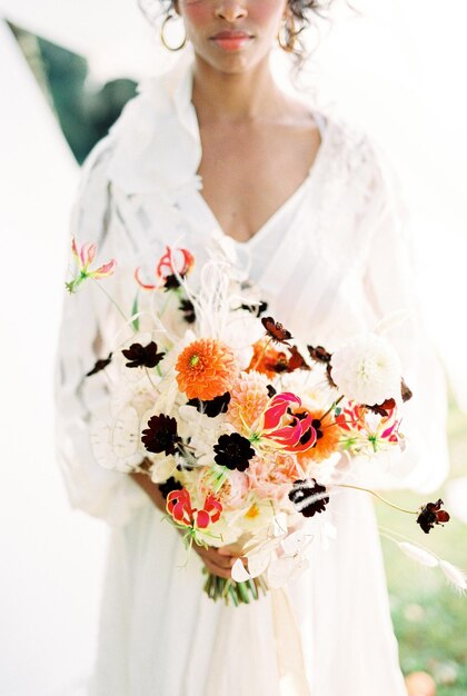 Photo femme en robe blanche avec un bouquet de fleurs gros plan