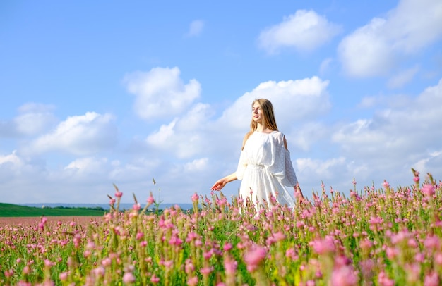 Femme en robe blanche sur un champ de sainfoin fleuri