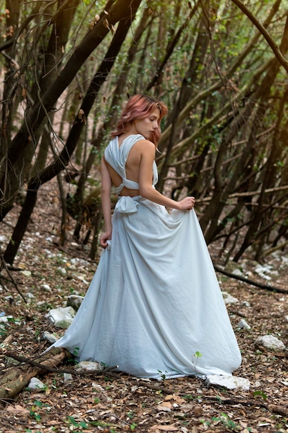 Une femme en robe blanche dans les bois