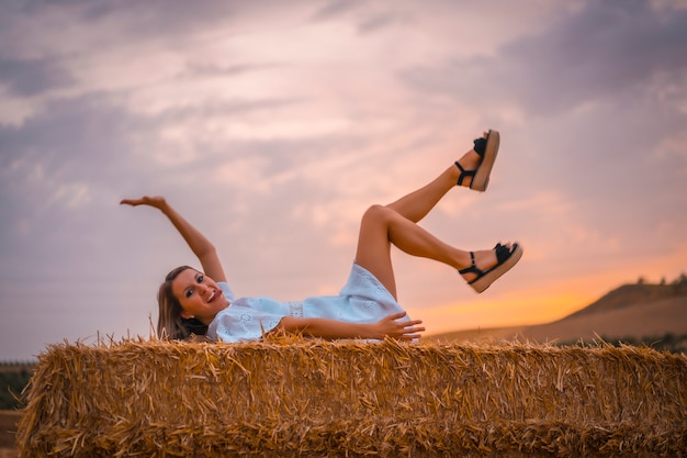 Femme en robe blanche dans un champ de paille sèche