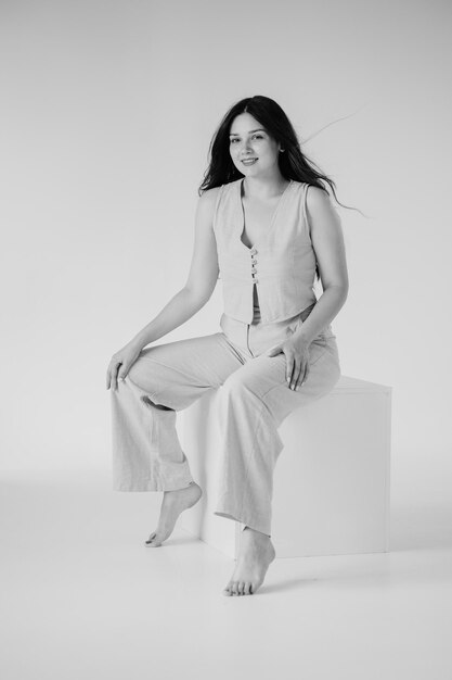 une femme en robe blanche est assise sur un tabouret blanc