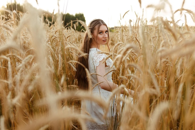 femme en robe blanche marchant le long du champ de blé tout en profitant du week-end