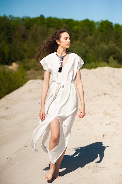 Femme en robe blanche marchant sur le sable