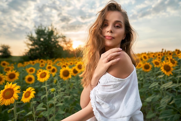 Femme en robe blanche posant sur le terrain avec des tournesols