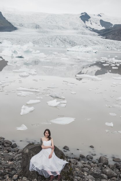 Femme en robe blanche se dresse sur fond de glaciers en Islande