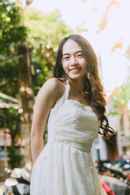 Photo une femme en robe blanche se tient devant un arbre