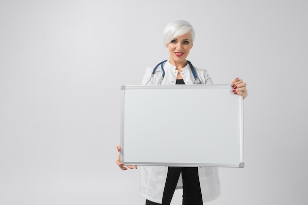 Femme en robe blanche avec un tableau magnétique dans ses mains. Une place pour une étiquette