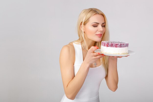 Femme en robe blanche tenant un gâteau