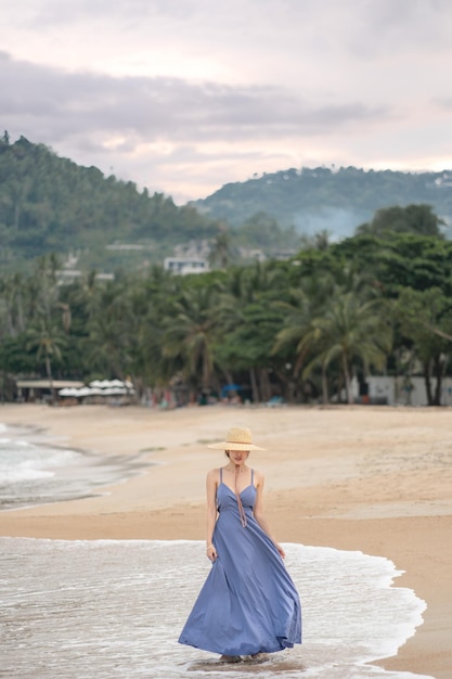 Femme en robe bleue pose sur la plage