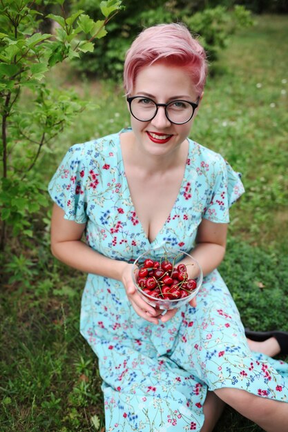 Femme en robe bleue tenant une poignée de cerises douces