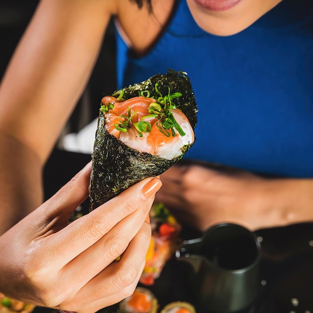 Photo une femme en robe bleue tient un rouleau de sushi avec un morceau de saumon dessus.
