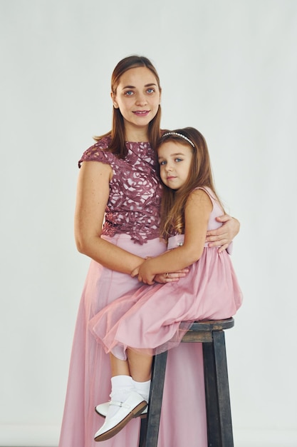 Femme en robe debout avec sa fille dans le studio avec un fond blanc