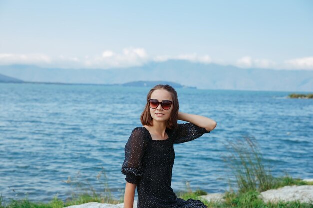 Femme en robe d'été et lunettes de soleil relaxantes sur la plage