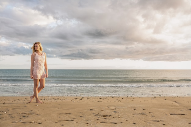 Femme en robe d&#39;été marchant sur la plage