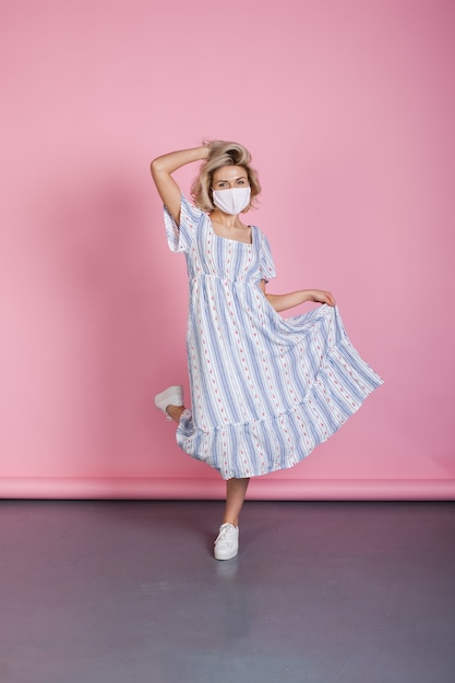 femme avec une robe d'été et un masque médical danse